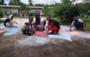 Coloriage à la craie de la fresque géante par les 6e du collège d'Iloni